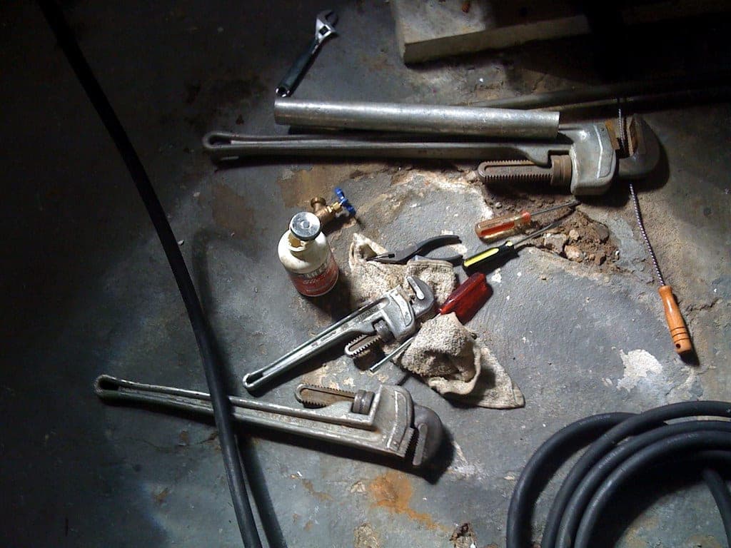 Hand tools laid out beside a sump pump installation